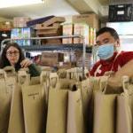 Student and teacher put groceries in bags at Food Bank.